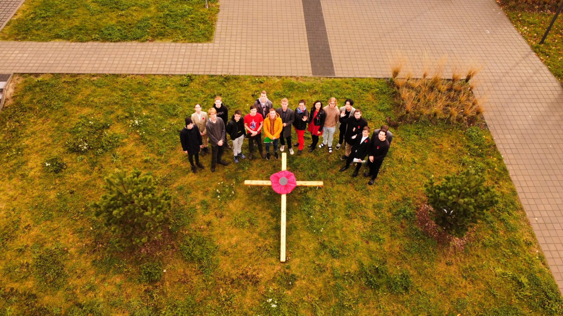 Společná fotku senátu u dřevěného kříže ozdobeného velkým vlčím mákem. Fotka byl focena z dronu.